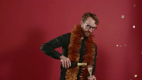Red-haired handsome man in glasses and a golden boa raises a glass of champagne. Stock Footage 221642909