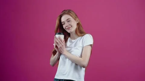 The red-haired, happy student satisfactorily drinks coffee from the paper cup Stock Footage 153976802