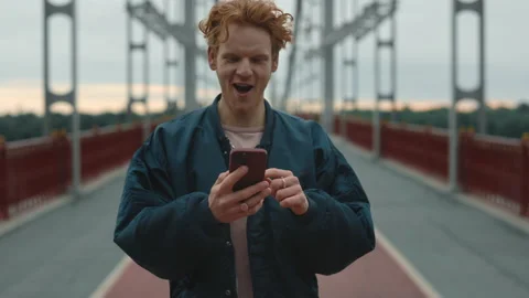 Red haired looking on mobile screen with happiness on face Video stock 162832053