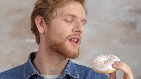 Red-haired man isolated on white biting donut eating joyful Stock Footage 121538839