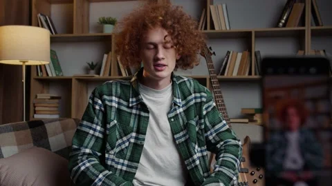 Red-haired man recording a video tutorial on how to play the guitar Stock Footage 233261496