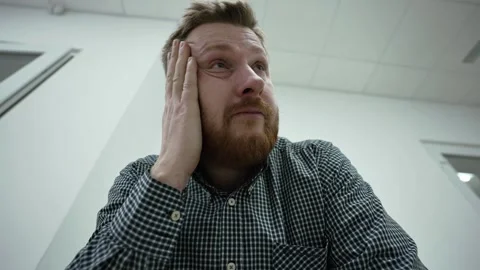 Red-haired middle-aged man sitting in office or at home and holding his head  Stock Footage 270522085
