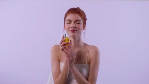 Red-haired model uses perfume spray and smiles at camera Stock-Footage 312443883