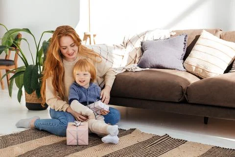 Red haired mom cheerfully prepares Christmas gifts with her son Stock Photos