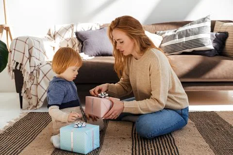 Red haired mom cheerfully prepares Christmas gifts with her son Stock Photos