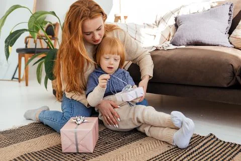Red haired mom cheerfully prepares Christmas gifts with her son Stock Photos