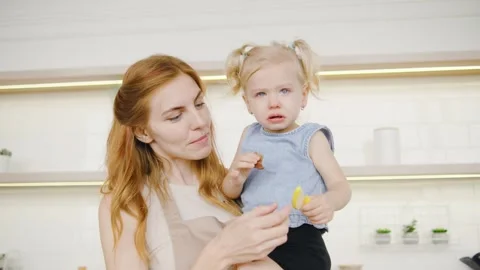 Red-Haired Mom Comforts Her Crying Little Daughter by Offering an Apple Slice Stock-Footage 289231653