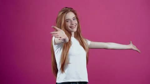 The red-haired, optimistic and smiling young woman waving her hands open for Stock Footage 154770982