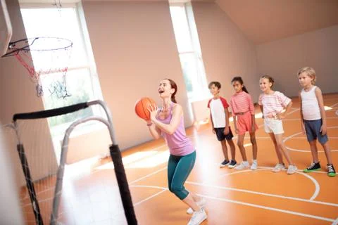 Red-haired PE teacher throwing ball into basket Stock-Fotos