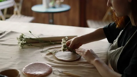 A red-haired potter makes flower prints on earthenware Stock Footage 209950534