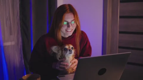 A red-haired programmer woman is engaged in working on her laptop while her 스톡 동영상 297552126