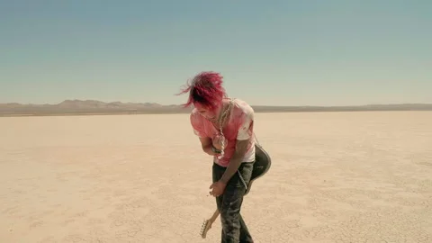 A red-haired punk wraps a chain around his neck, screaming in despair in desert Stock Footage 293118402