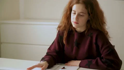 Red-haired schoolgirl does homework, reads, gets bored, looks out the window Video stock 160171602