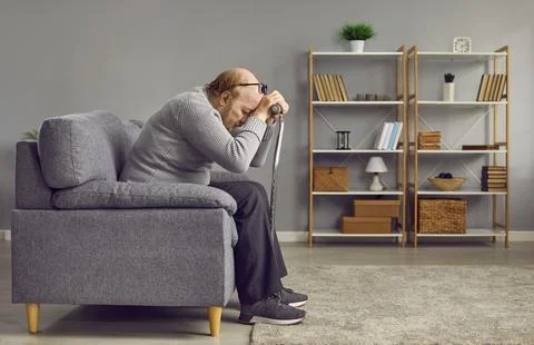 Red-haired, thoughtful, elderly man in gray warm sweater bowed his head, leaning Stock Photos