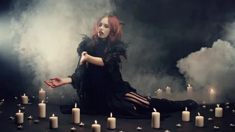 Red-haired witch sitting on floor in smoke, making energetic hand gestures to Stock Footage 144340937