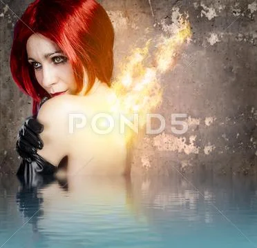 Red-haired woman with back fire on water effect Stock Photos