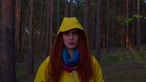Red haired woman looking at camera removing hood looking at sky Stock Footage 134878717