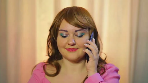 Red-haired woman at a table in a cafe eating pastries and talking on the phone. Stock Footage 121272934