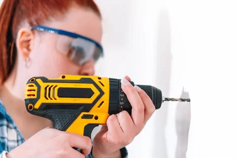 Red-haired woman using a drill at home Stock Photos