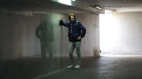 Red-haired young guy is waiting for someone in the underpass Vidéo 163354889