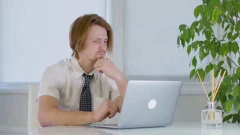 Red-haired young male worker in the office.listening carefully to video call Vidéo 239270230