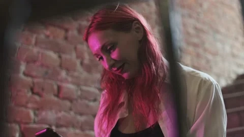 Red-haired young using smart phone sitting on stairs in red brick building Stock Footage 160984933