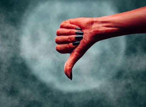 Red hand of a devil with thumb down gesture. Stock Photos