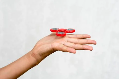 Red hand spinner. Boy playing a popular toy fidget spinner in his hand. Stres Stock Photos