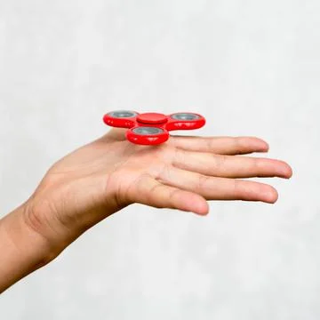 Red hand spinner. Boy playing a popular toy fidget spinner in his hand. Stres Stock Photos