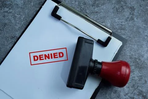 Red Handle Rubber Stamper and Denied text above paperwork Stock Photos