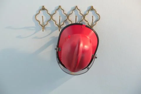 Red hardhat hanging on hook Stock Photos