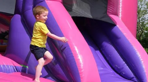 Red headed boy having fun playing on bouncy castle Stock Photos