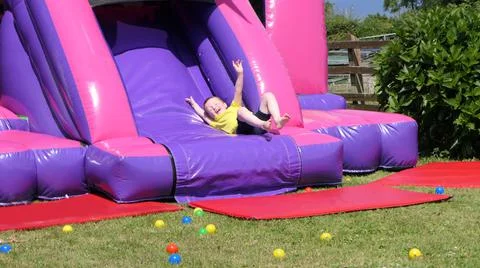 Red headed boy having fun playing on bouncy castle Stock-Fotos