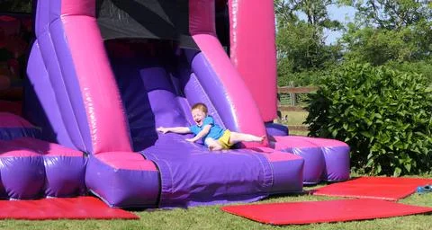 Red headed boy having fun playing on bouncy castle Stock Photos