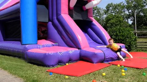Red headed boy having fun playing on bouncy castle Foto stock
