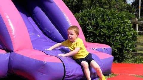 Red headed boy having fun playing on bouncy castle Stock Photos