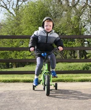 Red headed boy having fun playing on his bike in a garden Fotos Stock