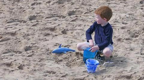Red headed boy playing on a sandy beach in Northern Ireland Holidays UK Stock Photos