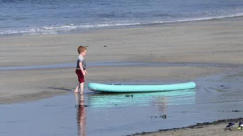 Red headed boy playing on a sandy beach in Northern Ireland Holidays UK Stock Photos