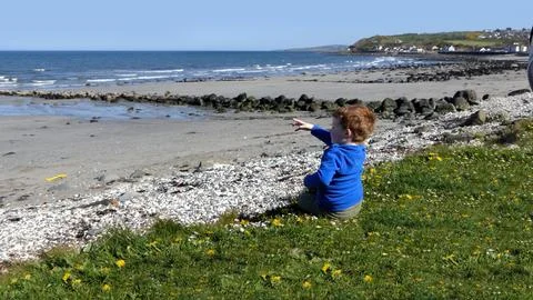 Red headed boy playing on a sandy beach in Northern Ireland Holidays UK Stock Photos
