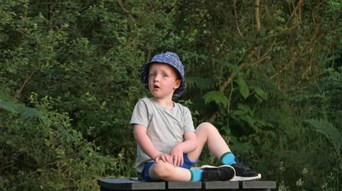Red headed boy with a puzzled look with a grey t-shirt on a table in Playpark Foto stock