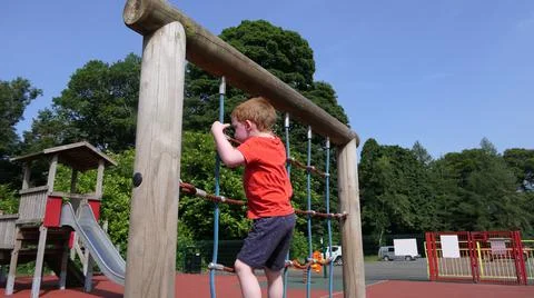 Red headed boy with a red t-shirt having fun having fun on a roap in a Playpa Stock Photos