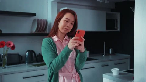 Red-headed pretty asian young woman in casual outfit using smartphone in the Stock Footage 131666981