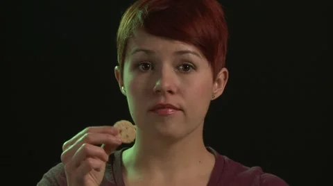 Red-Headed Woman Eats Chocolate Chip Cookies, Caucasian, Black Background Stock Footage 55520134