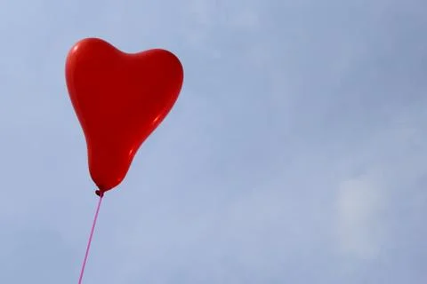Red heart balloon in front of the blue sky Stock Photos