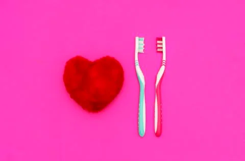 Red heart between two toothbrushes on pastel pink background. Male and female Stock Photos