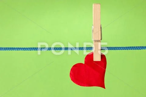 Red heart hung over a green background Stock Photos