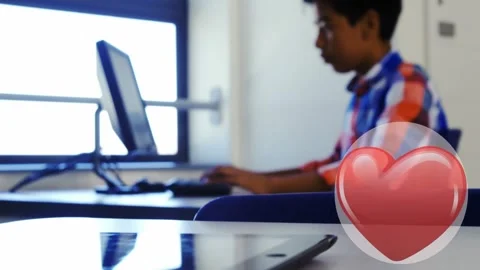 Red heart icon with copy space against indian boy using computer at school Stock Footage 329288700