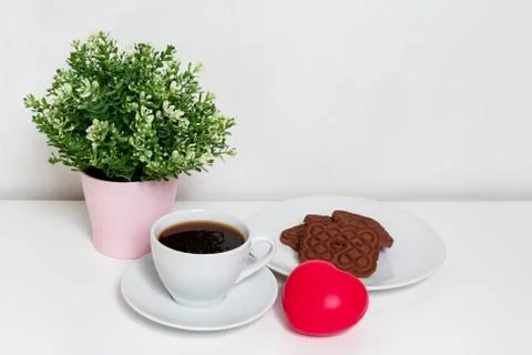 Red heart lying on white table near a cup of coffee and cookies, spring and v Stock Photos