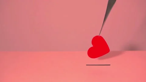 A red heart made of paper is held with tweezers and put in the slot Stock Footage 147487530